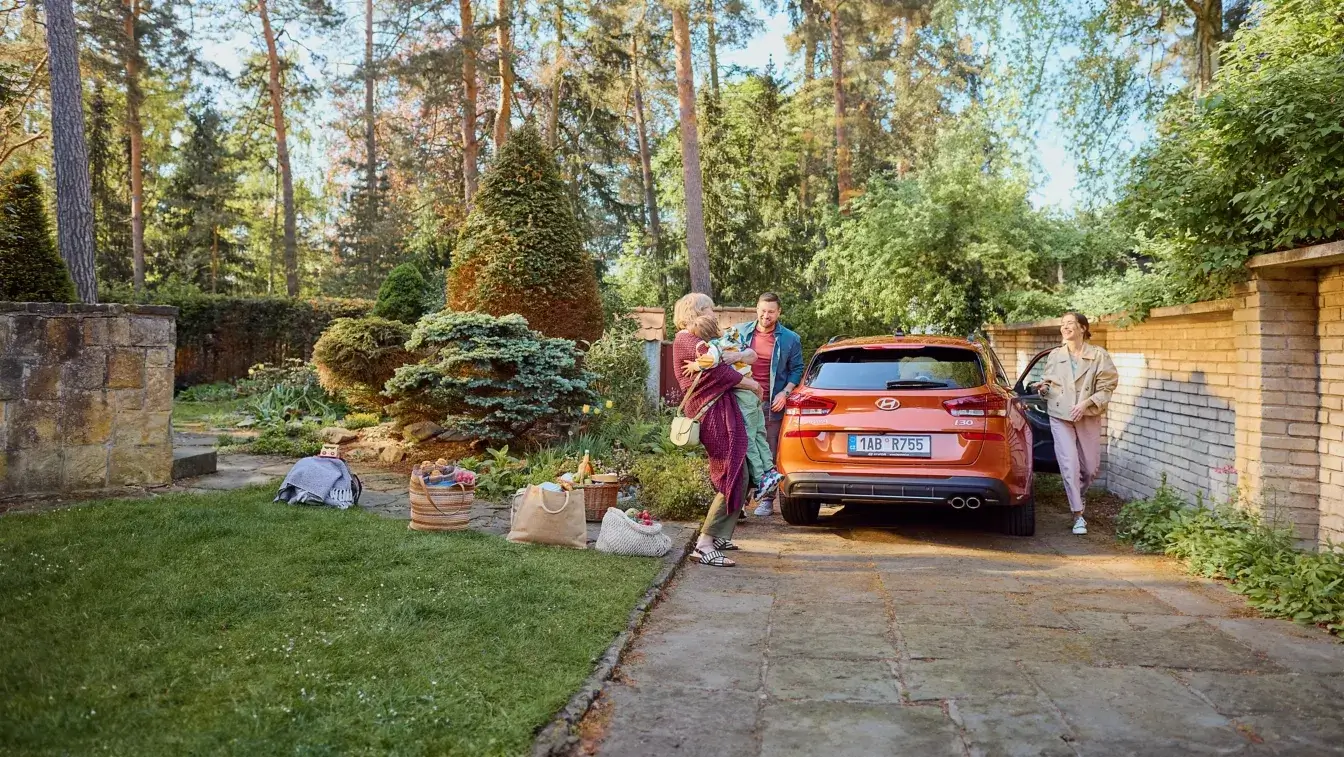 Rodina nakladá pikniková koše do oranžového Hyundai i30 kombi pred záhradou – akcia BEGAM Trnava