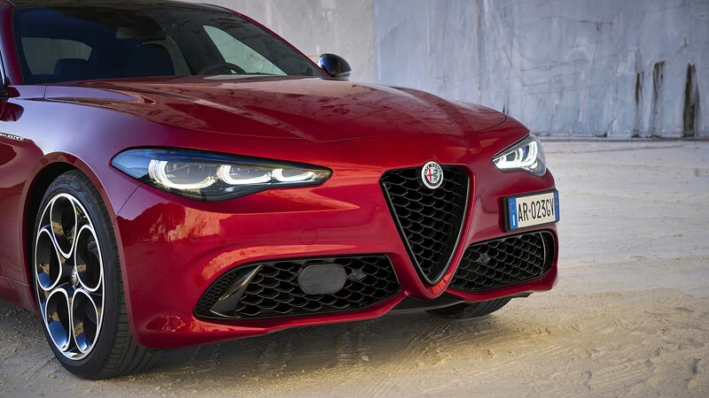 Detail prednej masky Scudetto a nárazníka červenej Alfa Romeo Giulia s diskami v štýle telefónneho ciferníka