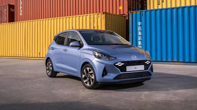 Svetlomodrý Hyundai i10 zaparkovaný pred farebnými prepravnými kontajnermi